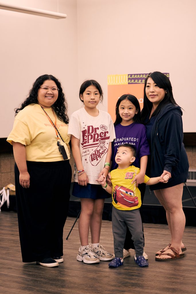 Mother with her three children smiling alongside their Family Educator.