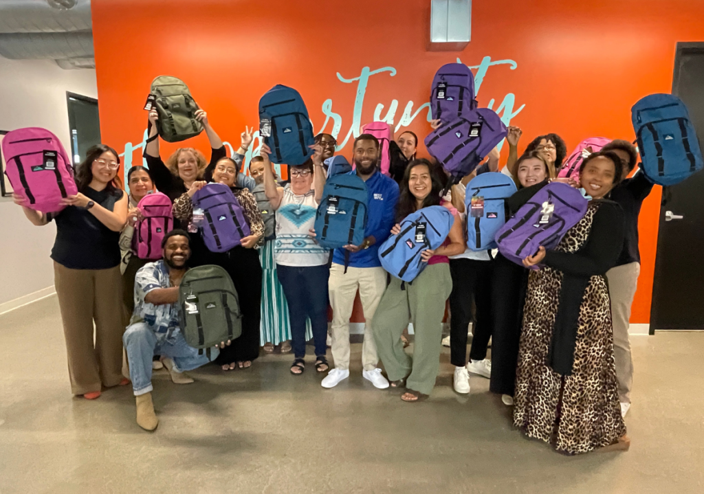 Way to Grow staff and community partners gather with donated backpacks and school supplies.