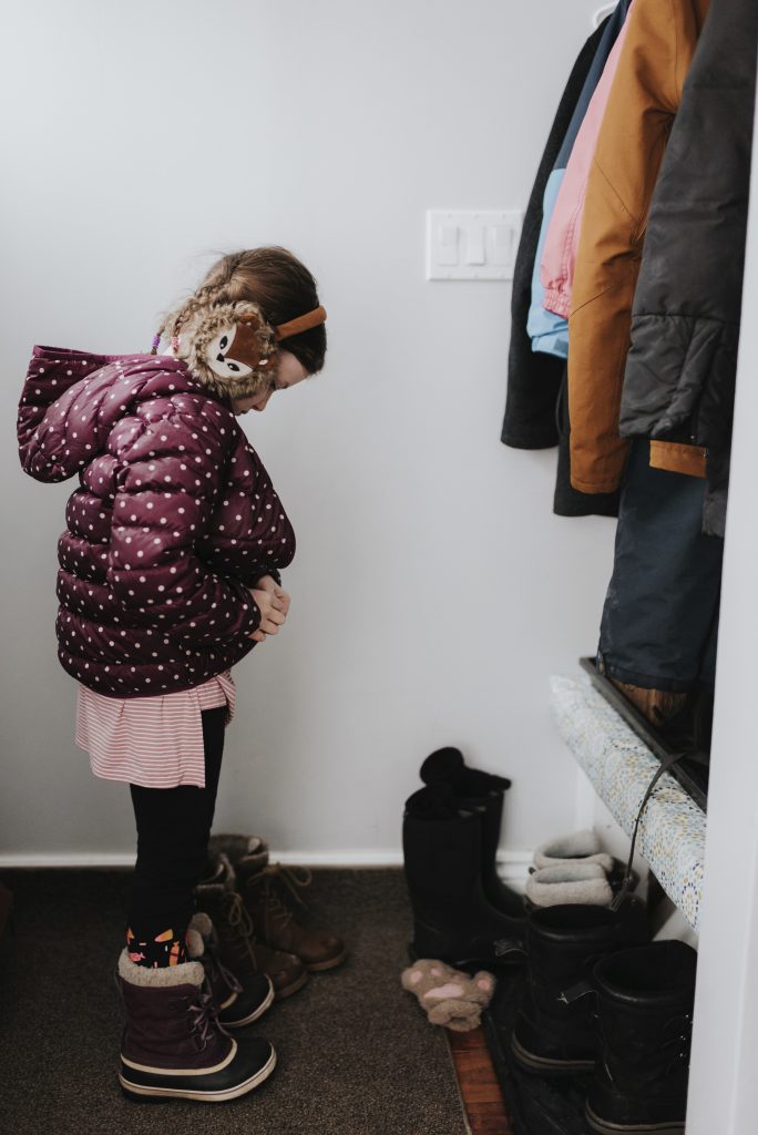 Girl putting on jacket in cloakroom