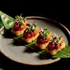Sushi bites topped with microgreens on a stoneware plate
